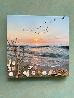 a beach scene with sea shells and birds flying over the ocean at sunset or dawn