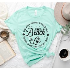 Beach Life T-Shirt, Beach Shirt, Beach Shirt, Beach Vibes Shirt, Beach Days T-Shirt, Bestie Beach Shirt, Summer Tee, Summer beach shirt How to Order?  1-Choose your t-shirt color, 2- Choose your size, 3- Select the quantity, 4- Click Add to Cart.  Production and shipping: * 100% airlume combed and ring-spun cotton, 32 singles 4.2 oz. * Solid colors are %100 cotton * Heathers are %52 cotton %48 polyester * Athletic Heather is combed and ring-spun cotton, 10% polyester * Seamless collar * Heat tra Tropical Graphic Print T-shirt For Beach, Green Letter Print T-shirt For Vacation, Vacation Beach Shirt With Palm Tree Print, Beachwear T-shirt With Graphic Print For Summer Adventures, Beach Party Short Sleeve Shirt, Tropical Relaxed Fit T-shirt For Beach Season, Short Sleeve Shirt For Beach Party Vacation, Short Sleeve Shirt For Beach Party, Summer Beach Camp Shirt With Graphic Print