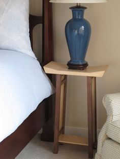 a blue vase sitting on top of a table next to a bed