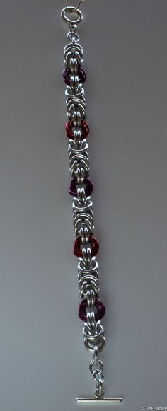 This is a chainmail bracelet made of Bright Aluminum (silver) and Anodized Aluminum (colors). It is a Byzantine chain interspersed with colored Mobius knots. I can lengthen or shorten it (additional $5/inch to lengthen), change the clasp (price depends on clasp selected), and change the color of the knots for $1/knot. Why aluminum? It's lightweight yet strong, making it comfortable to wear yet durable. It does not tarnish, but there are rare instances of a slight grey rub-off that can occur. This easily washes off. If the jewelry becomes dirty or dingy, it can be washed with soap and water or a vinegar and baking soda soak. I can make similar items in different weights or colors, as well as different materials such as stainless steel, sterling silver, copper, argentium, and more. If you do Mens Chainmail Bracelet, Chainmail Ornaments, Chainmail Jewelry Patterns, Chainmail Keychain, Diy Chainmail, Chainmail Diy, Chainmaille Jewelry Patterns, Chain Maille Patterns, Chainmail Patterns