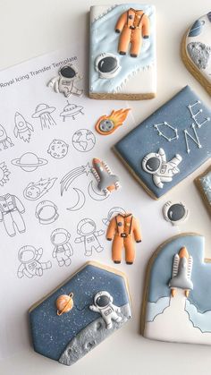 some cookies that are on top of a sheet of paper with space related items around them