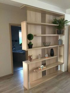 a wooden bookcase with plants and vases on top of it in a living room