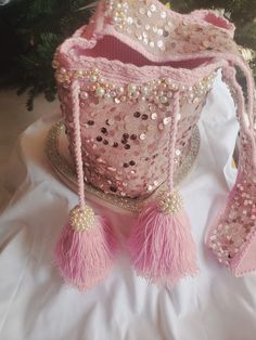 a pink purse with tassels and beads on it sitting next to a christmas tree