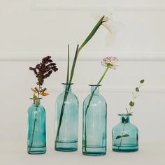 three vases with flowers in them sitting on a table