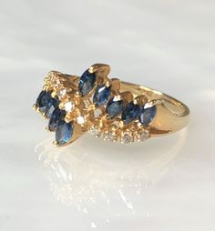 "Sapphire Ring, Sapphire Ring Vintage, Sapphire Ring For Women, Sapphire Diamond Ring, Marquise Sapphire Ring, Unique Eternity Band, 14k Ring A whimsical vintage treasure featuring 10 marquise shaped sapphires weighing 1.10 carats while accented by 0.23 carats of white diamonds set along a \"wave\" pattern in solid 14k yellow gold. * Ring size: US 6 1/2 * Complimentary resizing is available up to 3 sizes larger or smaller than stated size." Luxury Multi-stone Marquise Cut Rings, Luxury Marquise Cut Multi-stone Rings, Fine Jewelry Multi-stone Diamond Promise Ring, Multi-stone Sapphire Rings Marquise Cut, Cubic Zirconia Marquise-cut Multi-stone Diamond Ring, Marquise Cut Multi-stone Cubic Zirconia Diamond Ring, Multi-stone Cubic Zirconia Marquise Cut Ring, Marquise Cut Sapphire Multi-stone Rings, 14k Gold Cluster Diamond Ring Fine Jewelry