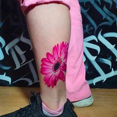 a woman's leg with a pink flower tattoo on it