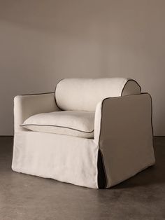 a white chair with black trim on the armrests and foot rest in front of a gray wall