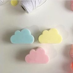 three cloud shaped soaps sitting on top of a white table next to yarn and scissors