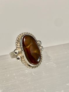 "Mexican Fire Agate set in Sterling Silver with a southwestern design work. The Fire Agate is a natural stone with a dark brown base color and bubbles of \"Fire\". This beautiful stone measures 19 mm by 10 mm. It is bezel set in Sterling Silver and has a rope design setting. The ring is measures 21mm long x 17mm wide. The band tapers to 4 mm Size- 7 Marked- none (tested and confirmed sterling Silver) Weight-4.58g" Amber Cabochon Agate Jewelry, Amber Agate Cabochon Ring, Amber Oval Cabochon Sterling Silver Ring, Fire Agate Ring, Orange Agate Cabochon Jewelry, Southwestern Style Cabochon Rings, Collectible, Montana Agate, Moss Agate Ring, Southwestern Design