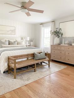 a bed room with a neatly made bed and a wooden bench in front of a window