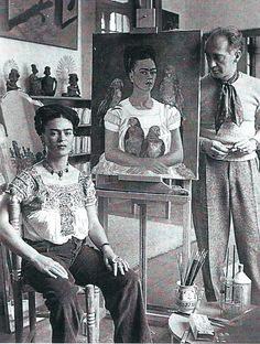 an old black and white photo of two people in front of art on easels