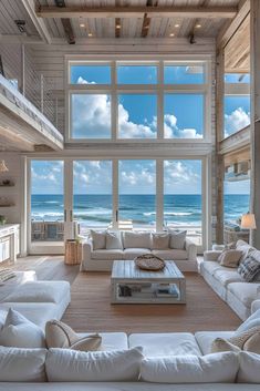 a living room with white couches and large windows overlooking the ocean in front of it