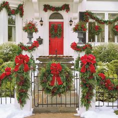 christmas wreaths on the front door of a house with red bows and poinsettis