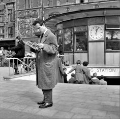 a man standing on the sidewalk reading a newspaper