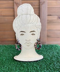 a wooden cutout of a woman's head with earrings on top of it