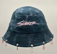 Slander Bucket Hat is the perfect addition to any festival or rave outfit. Made to be both stylish and functional, this bucket hat is a must-have clothes accessory for any fashion-forward individual.  Crafted with high-quality materials, this bucket hat guarantees long-lasting use while keeping your head cool and comfortable. Its sleek design allows you to pair it with a variety of outfits, making it a versatile piece in your fashion accessories collection. Whether you're out in the sun or dancing all night long, Slander Bucket Hat has got you covered - literally! Don't miss out on this trendy rave accessory! Affordable Cap For Music Festival, Cheap Festival Bucket Hat, Trendy Festival Bucket Hat, Summer Rave Festival Hats, Trendy Bucket Hat For Music Festival, Trendy Festival Bucket Hat With Short Brim, Adjustable Summer Rave Hats, Trendy Short Brim Bucket Hat For Festivals, Trendy Adjustable Bucket Hat For Music Festival