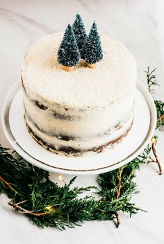 a cake with frosting and two small trees on top is sitting on a plate