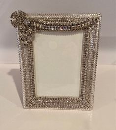 an ornate silver frame with beading on the edges and a bow at the top