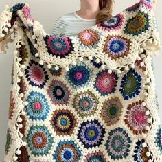 a woman is holding up a crocheted granny bag