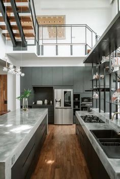 an open kitchen with stainless steel appliances and wood flooring, along with stairs leading up to the second floor