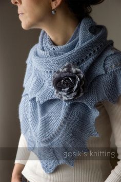 a woman wearing a blue knitted shawl with a flower on it