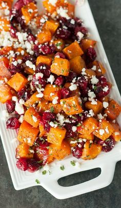 a platter filled with sweet potatoes, cranberries and feta cheese on top