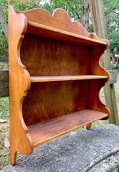 an old wooden book shelf sitting on top of a stone slab in front of a fence