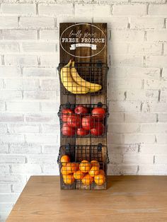 a fruit stand with apples, oranges and bananas on it in front of a brick wall