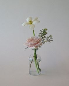 there is a vase with flowers in it on the white tablecloth and one flower has been placed inside