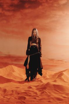 a woman standing in the middle of a desert