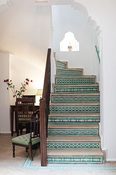 a set of stairs leading up to a dining room table and chairs in the background