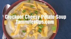 a red bowl filled with cheesy potato soup on top of a blue table