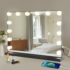 a vanity mirror with lights on it and a cell phone sitting next to the mirror