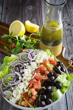 a salad with lettuce, tomatoes, black olives and feta cheese