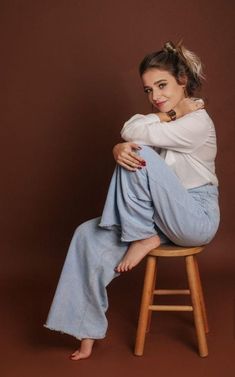 a woman sitting on top of a wooden stool