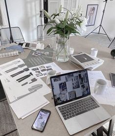 an open laptop computer sitting on top of a table next to a vase filled with flowers