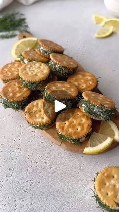 crackers are arranged on a wooden platter with lemon wedges