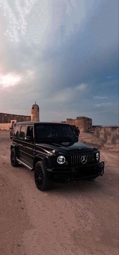 a black truck parked in the middle of a dirt road next to a silo