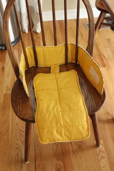 a wooden rocking chair with a yellow seat cover on it's armrests