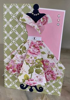 an origami card with a dress made out of paper and flowers on it