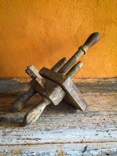 an old pair of wrenches sitting on top of a wooden table next to a yellow wall