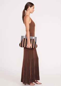 The Alba Frame Clutch is an oversized soft clutch with a structured wooden frame and turnlock closures. This style features an interior zipper pocket and a removable mirror. Details: 72% Polyester, 28% Viscose Striped raffia clutch with wooden frame 14.8" W x 9.13" H x 2.6" D Structured Brown Shoulder Bag For Evening, Chic Top Handle Clutch With Leather Handles, Chic Staud Shoulder Bag With Leather Handles, Leather Handle Pouch Clutch For Evening, Evening Clutch With Leather Handles, Brown Clutch With Detachable Handle, Chic Staud Shoulder Bag For Travel, Modern Brown Clutch Evening Bag, Elegant Staud Bags With Leather Handles