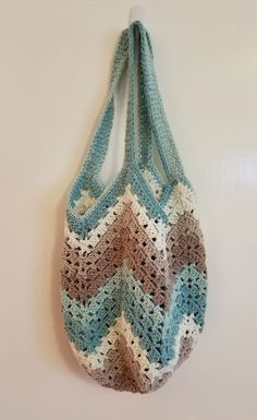 a crocheted bag hanging on the wall next to a white wall with a hook