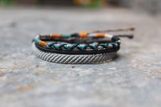 two bracelets sitting on top of a stone surface next to each other with different colored beads