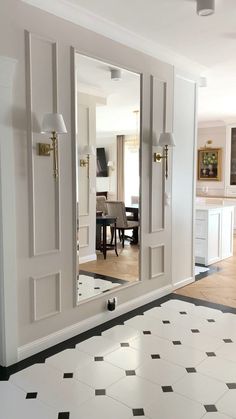 an open door leading to a dining room with black and white floor tiles on the floor