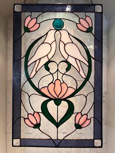 a stained glass window with flowers and leaves on it's side, hanging from the wall