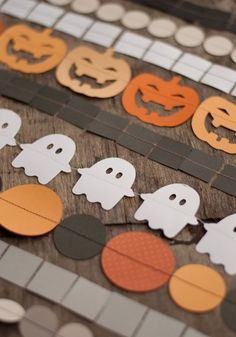 paper pumpkins and ghost cutouts on a wooden table with polka dotes in the background