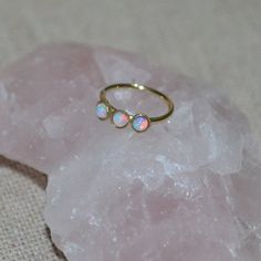 a close up of a ring on top of a piece of pink rock with white opals