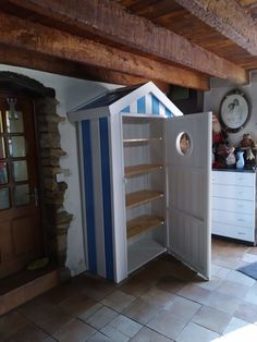 a small white and blue storage cabinet in the middle of a room with stone flooring