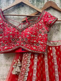 A three-piece red bridal sharmily embroidered lehenga set from the Priti Sahni collection. This beautiful and graceful georgette red butti bridal panel lehenga with a heavy border of gota, pearl, sequin, zari detail is paired with a red raw silk blouse with zardozi, sequin, & hand-embroidery work. The zari panelled lehenga has side hanging ball tassels to the waistline. And the blouse has a sequin-bead tassel tie-up at the back. This outfit is completed with a red tulle sequin butti dupatta with Red Resham Embroidery Pre-draped Saree For Wedding, Red Dori Work Sharara For Designer Wear, Red Sharara With Dori Work For Designer Wear, Designer Red Dori Work Sharara, Red Chinon Sets With Mirror Work, Red Saree Set With Mirror Work, Semi-stitched Red Sets With Mirror Work, Red Anarkali Set With Mirror Work In Art Silk, Red Art Silk Anarkali Set With Mirror Work